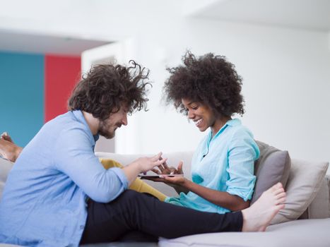 Young multiethnic couple sitting on a sofa in the luxury living room, using a tablet computer