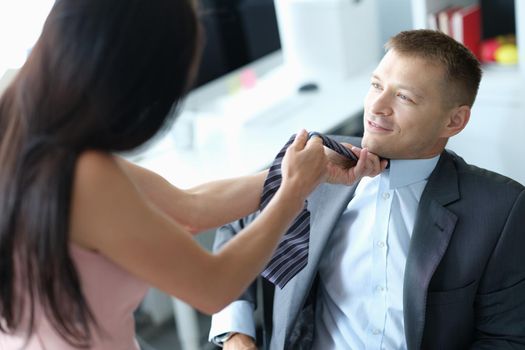 Female supervisor pulls tie of young employee. Flirting workplace concept