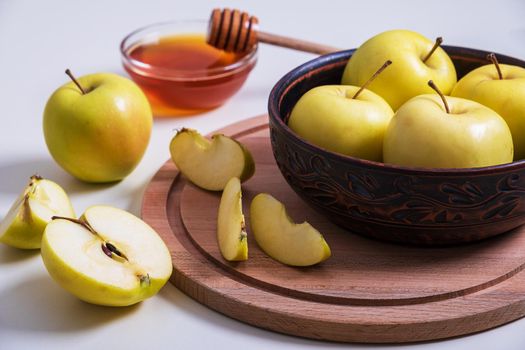 Fresh ripe whole and cut yellow apples with honey lie on table. Selective focus.