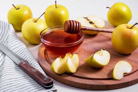 Fresh ripe whole and cut yellow apples with honey lie on table. Selective focus.