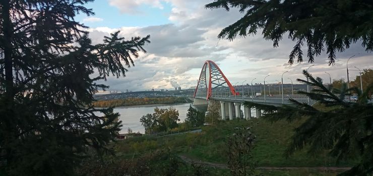 Red arch of the cable-stayed suspension bridge over the wide Ob River. Novosibirsk, Russia. Red suspension bridge over the Ob River. Bugrinsky bridge over the Ob River.