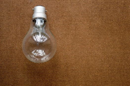 Light bulb placed over Brown Color Hard cork board. Creative background design ideas for business finance and industry.