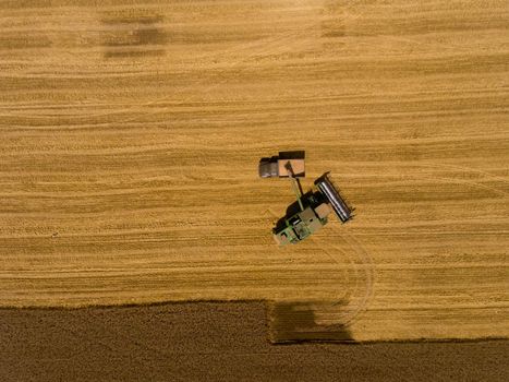 Harvester machine working in field. Aerial view. Top view.