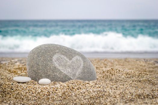 Stone with a heart symbol on the sand of the sea beach. The concept of Valentine's Day and love.