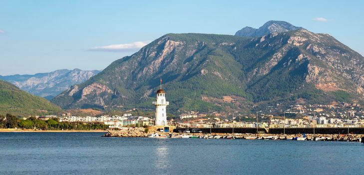 Turkey, Alanya - November 9, 2020: The old lighthouse in the port of Alanya against the backdrop of beautiful mountains. View from the sea.