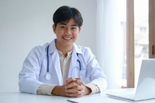 Confident young male doctor at office desk. 