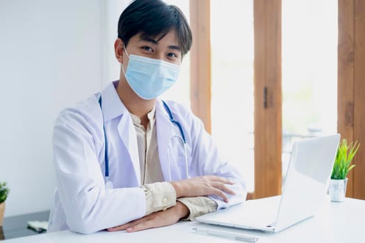 Confident young male doctor at office desk. 