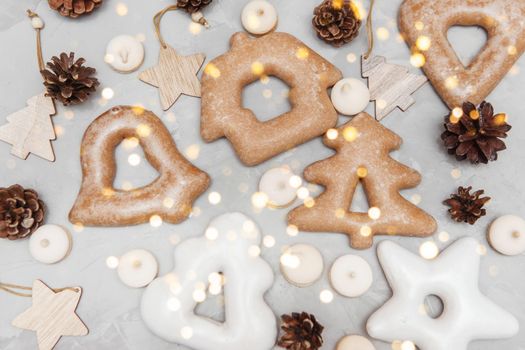Banner for Christmas and New Year gingerbread stars, houses, Christmas trees, toys on a gray concrete background, Christmas lights bokeh in the foreground.