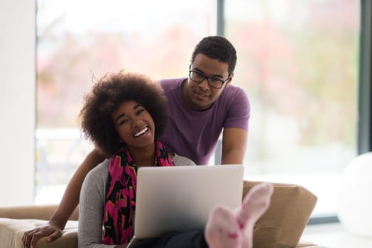 Happy young african american couple shopping online through laptop using credit card at home