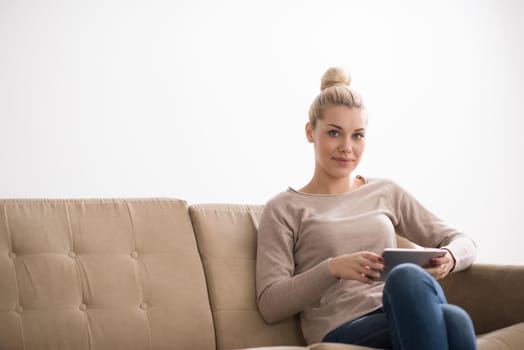 young happy woman sitting on sofa with tablet computer at luxury home