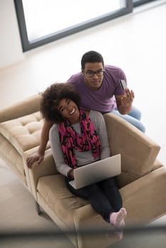 Happy young african american couple shopping online through laptop using credit card at home