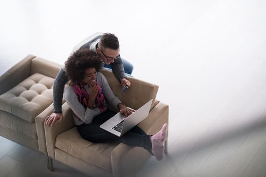 Happy young multiethnic couple shopping online through laptop using credit card at home