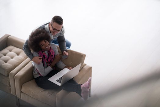 Happy young multiethnic couple shopping online through laptop using credit card at home