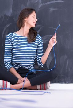 portrait of a young woman holding a internet cable in front of chalk drawing board