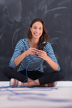 portrait of a young woman holding a internet cable in front of chalk drawing board