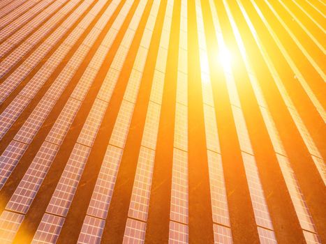 Aerial top view of a solar panels power plant. Photovoltaic solar panels at sunrise and sunset in countryside from above. Modern technology, climate care, earth saving, renewable energy concept