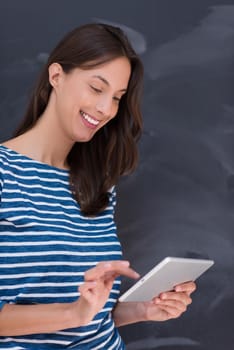 Happy young woman using tablet computer in front of chalk drawing board