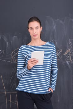 Happy young woman using tablet computer in front of chalk drawing board