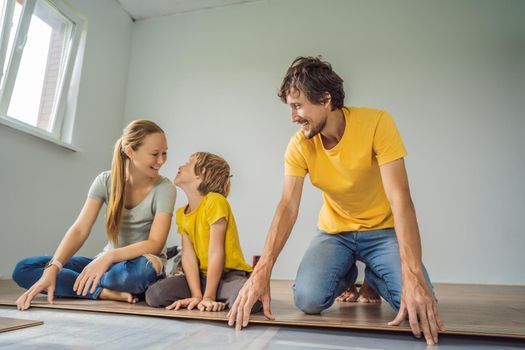 Happy family installing new wooden laminate flooring on a warm film floor. Infrared floor heating system under laminate floor.