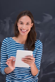 Happy young woman using tablet computer in front of chalk drawing board