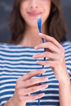 portrait of a young woman holding a internet cable in front of chalk drawing board