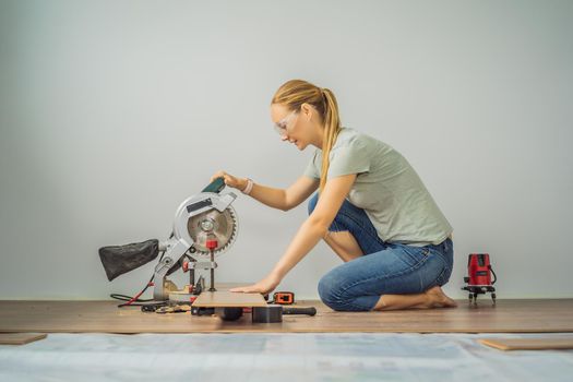 Married couple installing new wooden laminate flooring on a warm film floor. Infrared floor heating system under laminate floor.