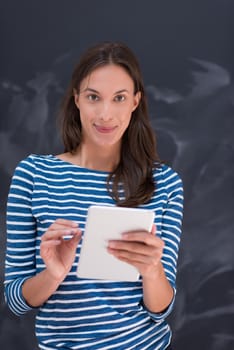 Happy young woman using tablet computer in front of chalk drawing board