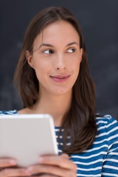 Happy young woman using tablet computer in front of chalk drawing board