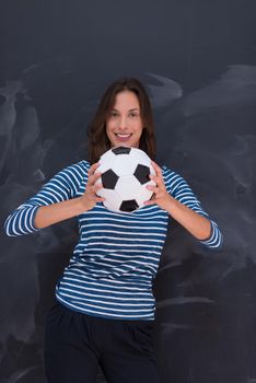 portrait of a young woman holding a soccer ball in front of chalk drawing board