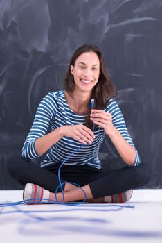 portrait of a young woman holding a internet cable in front of chalk drawing board
