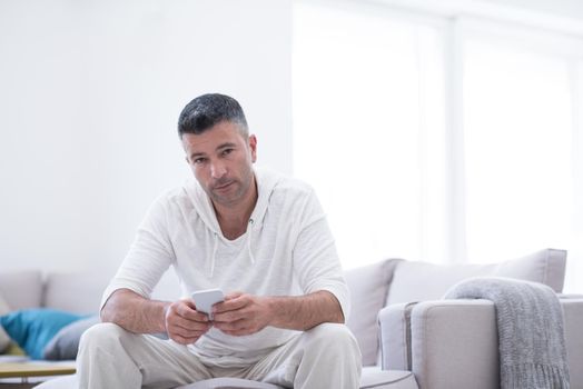 Handsome casual young man using a mobile phone at luxurious home