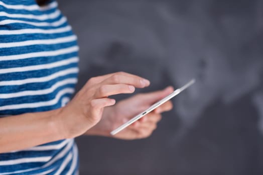 Happy young woman using tablet computer in front of chalk drawing board