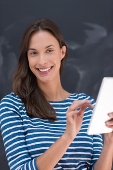 Happy young woman using tablet computer in front of chalk drawing board