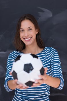 portrait of a young woman holding a soccer ball in front of chalk drawing board