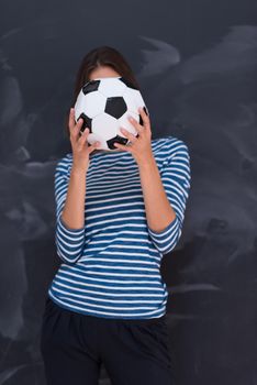 portrait of a young woman holding a soccer ball in front of chalk drawing board