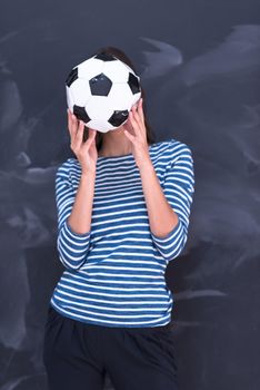 portrait of a young woman holding a soccer ball in front of chalk drawing board