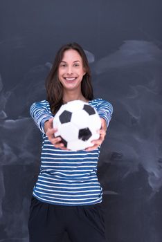 portrait of a young woman holding a soccer ball in front of chalk drawing board