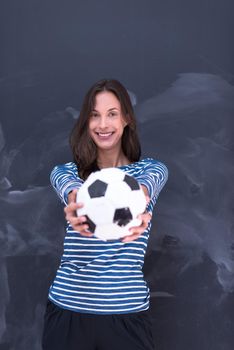 portrait of a young woman holding a soccer ball in front of chalk drawing board