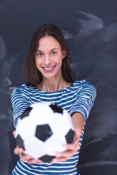 portrait of a young woman holding a soccer ball in front of chalk drawing board