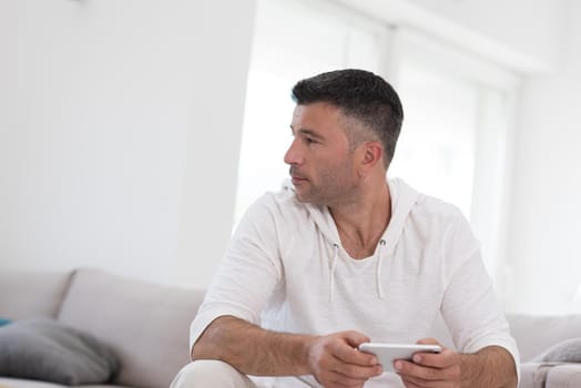 Handsome casual young man using a mobile phone at luxurious home