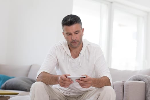 Handsome casual young man using a mobile phone at luxurious home