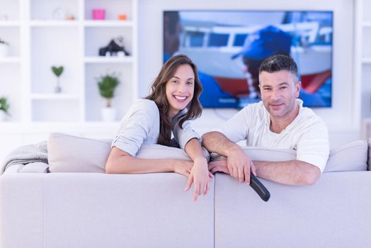 Young couple on the sofa watching television together in their luxury home