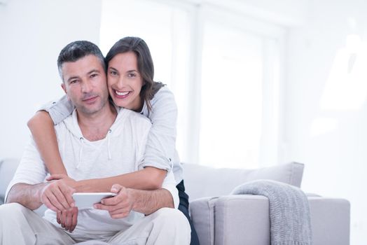 Young happy couple using mobile phone at home together, looking at screen, smiling.