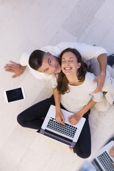 top view of a young couple relaxing at home with tablet and laptop computers reading on the floor