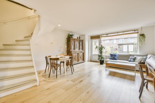 Cozy large room with a living and dining area and a large solid staircase