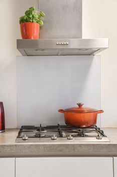 Cozy kitchen in daylight with gas hob and bright red ceramic saucepan