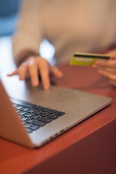 Young woman holding credit card and using laptop computer. Online shopping concept