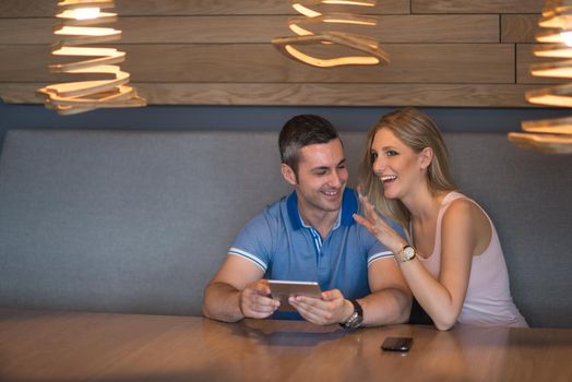 Young couple using tablet computer at luxury home together, looking at screen, smiling.