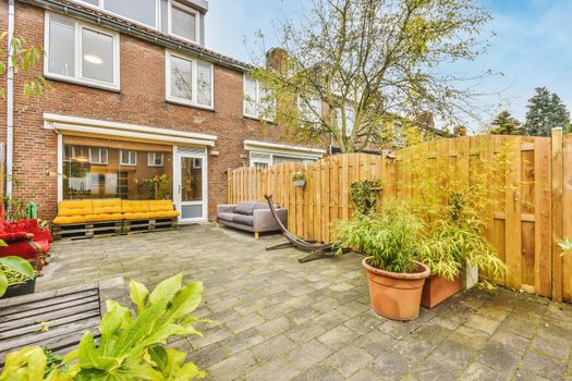 Cozy courtyard of a house with pots of flowers and a bright scarlet velvet sofa