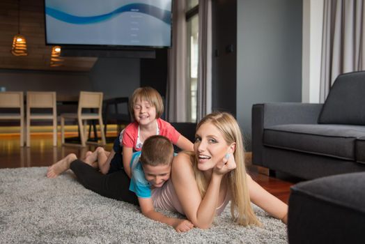 Happy Mother with kids having fun on the floor at home